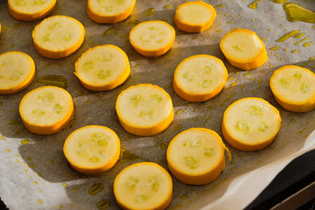 Sliced tasty and fresh yellow zucchini on baking paper with olive oil preparing baked zucchiniの写真素材