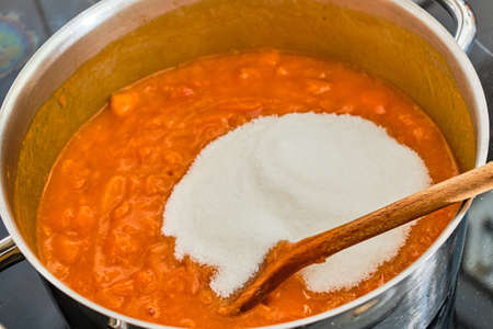 Cooking tasty apricots with sugar in pot preparing homemade marmeladeの写真素材