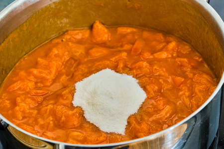 Cooking tasty apricots with gelling sugar in pot preparing homemade marmeladeの写真素材