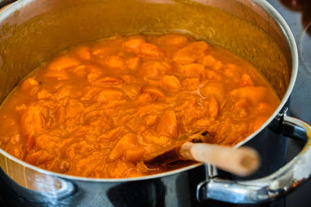 Cooking apricots in pot with wooden spoon preparing homemade marmeladeの写真素材