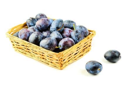 Tasty and fresh violet plum fruit in wooden basket isolated on white backgroundの写真素材