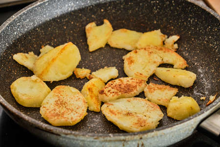 Cooking homemade tasty fried potatoes on frying pan close upの写真素材