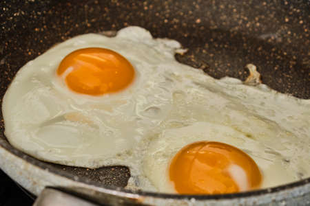 Cooking tasty fried eggs on frying panの写真素材