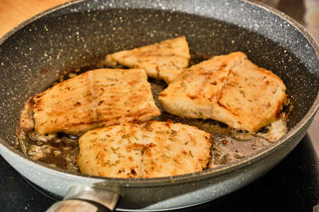 Cooking tasty luce fillet with rosemary herb on frying pan close up detailの写真素材