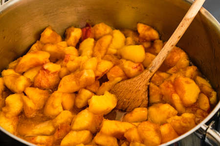 Cooking peach fruit in metal pot and stir with wooden spoon preparing homemade marmaladeの写真素材