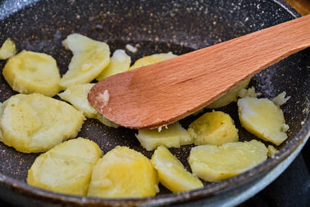 Cooking homemade tasty fried potatoes on frying pan close upの写真素材