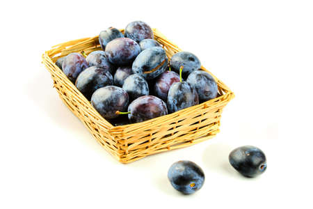 Tasty and fresh violet plum fruit in wooden basket isolated on white backgroundの写真素材