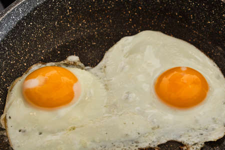 Cooking tasty fried eggs on frying panの写真素材