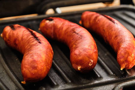 Cooking tasty pork sausages on metal electric grill close upの写真素材