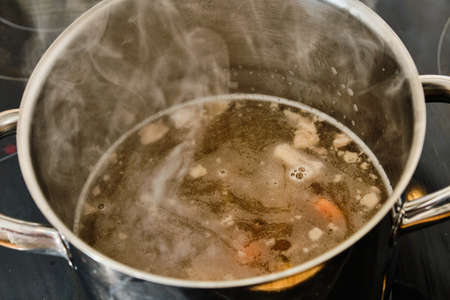 Preparing homemade tasty beef soup in cooking pot on cookerの写真素材
