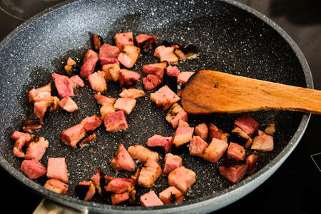 Cooking tasty pork smoked bacon meat pieces on hot frying panの写真素材