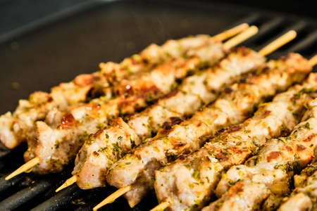 Cooking homemade tasty pork meat souvlaki spiced with oregano on grill, traditional greek foodの写真素材