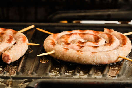 Cooking tasty white spiral bavarian sausages on electric grill close up detailの写真素材