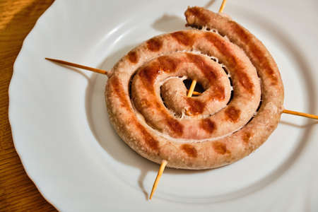Tasty white bavarian spiral sausages on white plate on wooden tableの写真素材