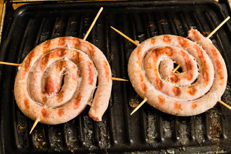 Cooking tasty white spiral bavarian sausages on electric grill close up detailの写真素材