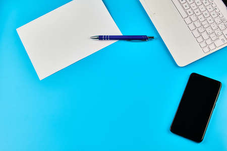Business flatlay with laptop, paper pencil and smartphone on blue backgroundの写真素材