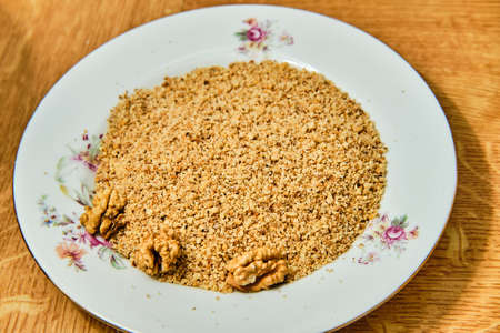 Tasty grated walnuts on plate on wooden tableの写真素材