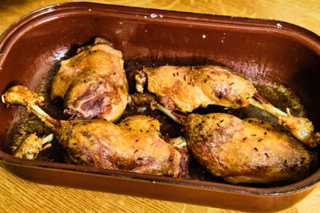 Roasted tasty duck lengs in metal cooking pan on wooden tableの写真素材