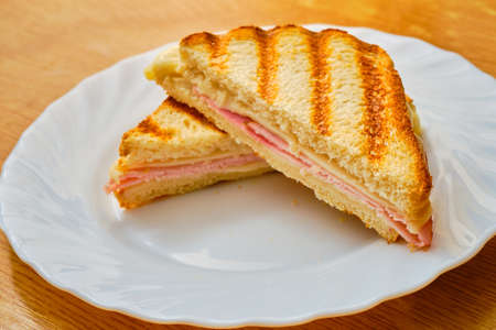 Tasty sliced toast with ham and cheese on white plateの写真素材