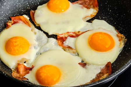 Cooking tasty fried eggs with bacon on frying panの写真素材
