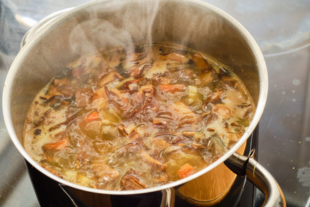 Cooking czech souppotato with potatoes, carrot and mushrooms in cooking pot on stove