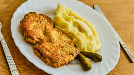 Tasty inside out roest beef schnitzel with mashed potatoes on white plate on wooden table with fork and knifeの写真素材