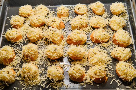 Preparing oven baked appetizers - pastry with butter, cheese and cumin on baking tray