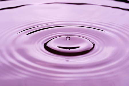 Rippled water surface with water drop above in purple colors - joy abstractの写真素材