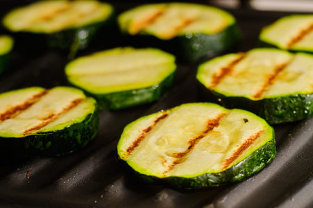 Cooking tasty sliced zucchini on grill preparing vegetable vegetarian snackの写真素材