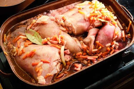 Preparing rabbit meat with vegetables and red wine on cooking pan before baking in ovenの写真素材