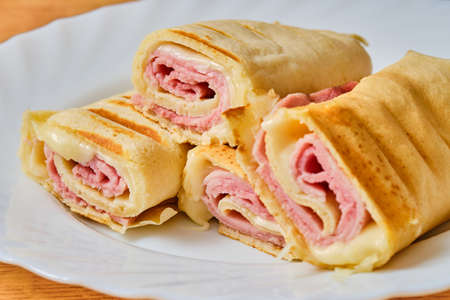 Tasty grilled pancakes with ham and cheese on white plateの写真素材