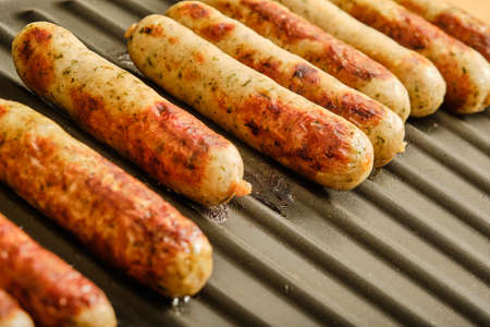 Preparing tasty nuremberg sausages on hot grillの写真素材