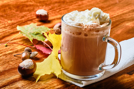 Hot tasty cacao drink with cream in glass cup in Autumnの写真素材