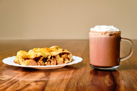 Tasty apple strudel on plate with cocoa drink in glass on wooden tableの写真素材
