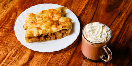 Tasty apple strudel on plate with cocoa drink in glass on wooden tableの写真素材
