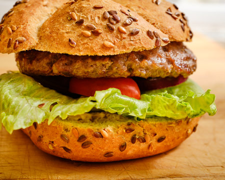 Grilled tasty beef meat in bun with salad and cherry tomatoes on wooden desk detailの写真素材