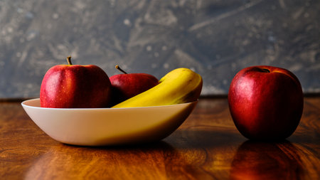 Still life with red apples and banana fruit in bowl on wooden tableの写真素材