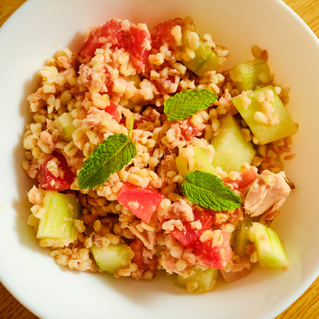 Tasty bulgur salad with tuna fish, cucumber and tomato with green herb in bowlの写真素材