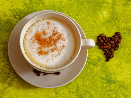 Cappuccino coffee drink with cinnamon in white and heart shaped coffee beansの写真素材