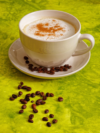 Cappuccino coffee drink with cinnamon in white cup on green backgroundの写真素材