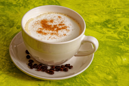 Cappuccino coffee drink with cinnamon in white cup on green backgroundの写真素材