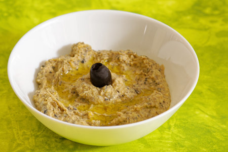 Tasty chickpeas and black olive hummus in white bowlの写真素材