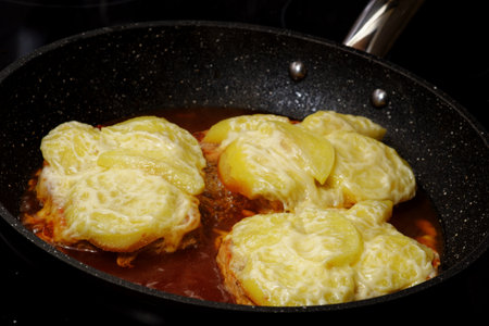 Cooking tasty pork meat steak with sliced apple and cheese on frying panの写真素材