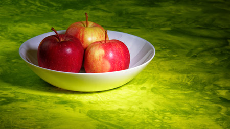 Still life with red apples and bowl on green backgroundの写真素材