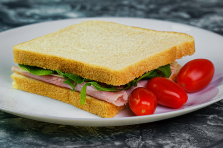 Tasty sandwich with ham, cheese and salad on white plateの写真素材
