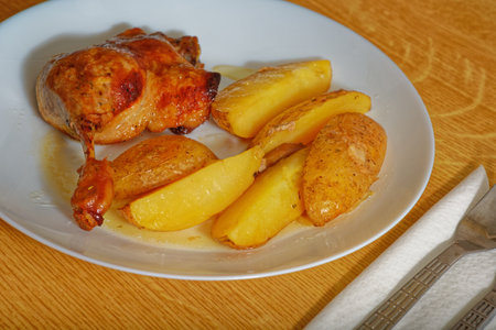 Tasty oven baked roast duck leg with potatoes on white plateの写真素材