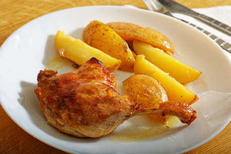 Tasty oven baked roast duck leg with potatoes on white plateの写真素材