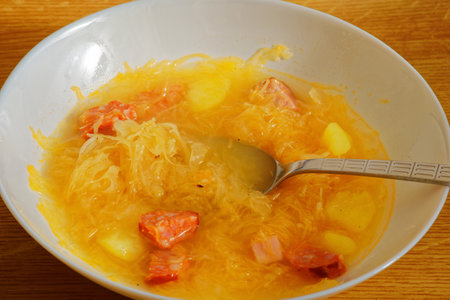 Tasty homemade cabbage soup on white plate with spoonの写真素材