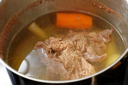 Preparing tasty beef broth with meat and vegetables in a slow boiling cooking potの写真素材