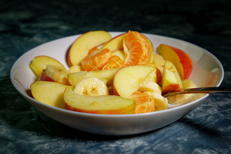 Tasty fruit salad in white bowl on dark blue backgroundの写真素材